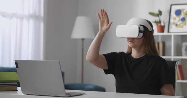 Genç kadın kullanıcı, kontrol için el hareketleriyle hareket ederek, modern vr baş montajlı ekran dizüstü bilgisayar ekranını izliyor — Stok video