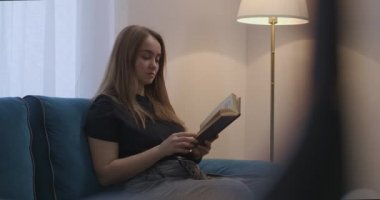 Genç ve güzel bir kadın pazar akşamı evde kitap okuyor. Zeki bayan romanla rahatlıyor.