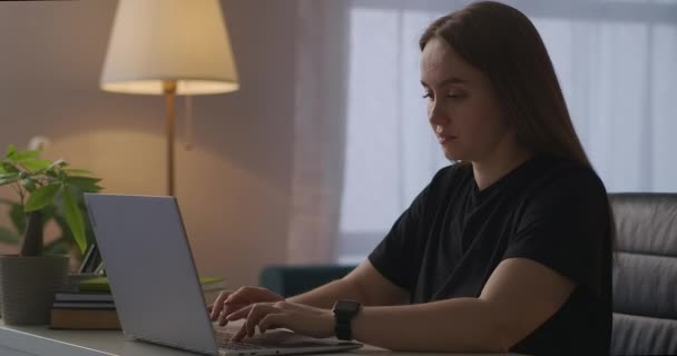 Ung kvinna avslutar arbetet med laptop, stänga locket och släcka ljuset i rummet, fjärrarbete hemma — Stockvideo