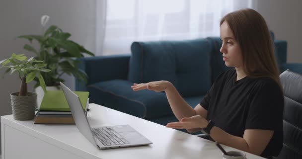 通过视频聊天进行在线交流，女人正坐在客厅里对着笔记本电脑的网络摄像头说话 — 图库视频影像