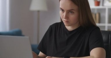 Bayan öğrenci ödev yapıyor, not defterine notlar yazıyor ve dizüstü bilgisayarda web sitelerini ve e-öğrenimi gösteriyor.