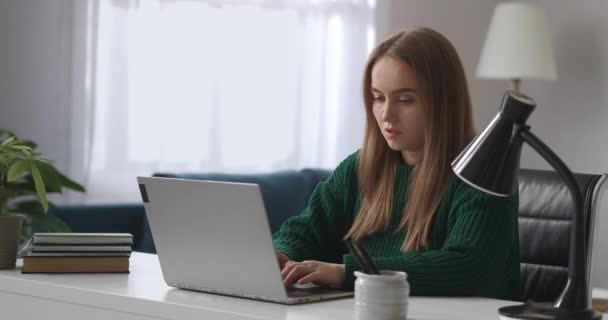 Συγκεντρωμένη γυναίκα εργάζεται στο σπίτι, πληκτρολογώντας κείμενο στο πληκτρολόγιο του φορητού υπολογιστή, απομακρυσμένη εργασία για νέες γυναίκες σε άδεια μητρότητας — Αρχείο Βίντεο