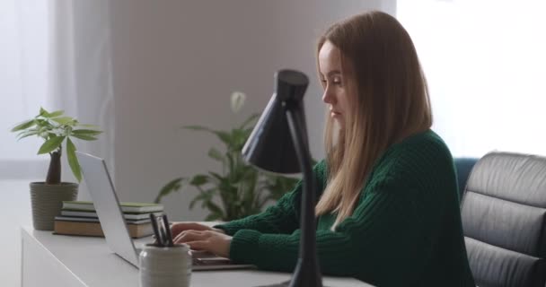 Young woman is working alone in big offices at daytime, typing text on keyboard of modern laptop with wireless internet connection — Stock Video