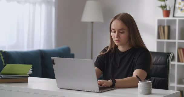 Freelancer woman is working with laptop in home, typing text on keyboard of laptop, office place in living room — Stock Video