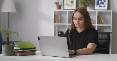 Siyah tişörtlü ciddi bir kadın, merkez ofiste dizüstü bilgisayarla çalışıyor, sosyal ağlar, smm veya seo uzmanlarıyla online sohbet yazıyor.