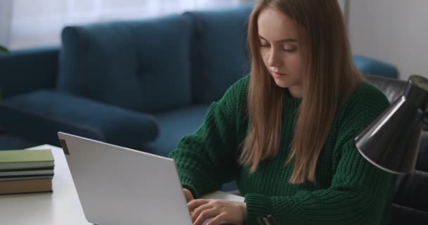 Wanita muda chatting online di jaringan sosial dengan laptop, mengetik dan mengirim pesan, potret wanita muda di meja di kamar — Stok Video