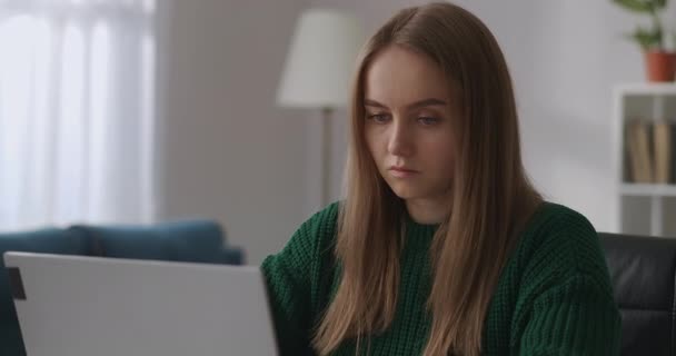 Молодая красивая женщина одета зеленый свитер общается через онлайн чат в социальных сетях, печатая на ноутбуке — стоковое видео