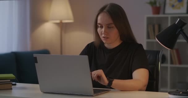 Женщина работает с ноутбуком дома, чувствуя усталость и боли в голове и шее, закрывая крышку ноутбука и расслабляя — стоковое видео