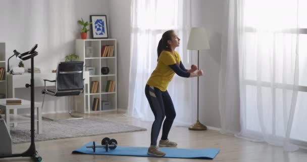 Adolescente está treinando sozinho na sala de estar, fazendo aeróbica e ginástica de manhã, mantendo-se em forma, treino — Vídeo de Stock