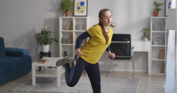 Αερόβια προπόνηση στο σπίτι, έφηβος κορίτσι κάνει ασκήσεις με βήμα και κίνηση των χεριών, υγιεινό τρόπο ζωής και γυμναστήριο στο σπίτι — Αρχείο Βίντεο