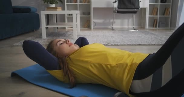 Mulher está fazendo exercícios para músculos abdominais, levantando o tronco deitado no chão, treinando em casa sozinho — Vídeo de Stock