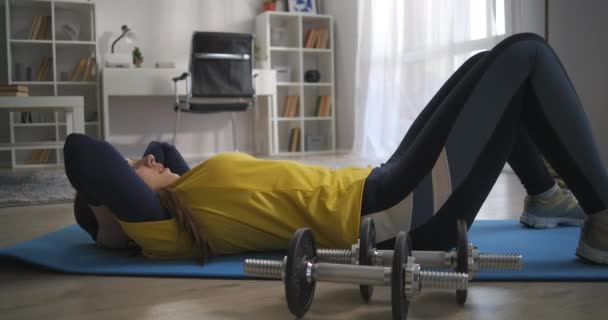 Chica adolescente deportiva haciendo ejercicios para los músculos abdominales, levantando el torso tumbado en el suelo, aptitud en el hogar y estilo de vida helada activa, entrenamiento en el apartamento — Vídeos de Stock