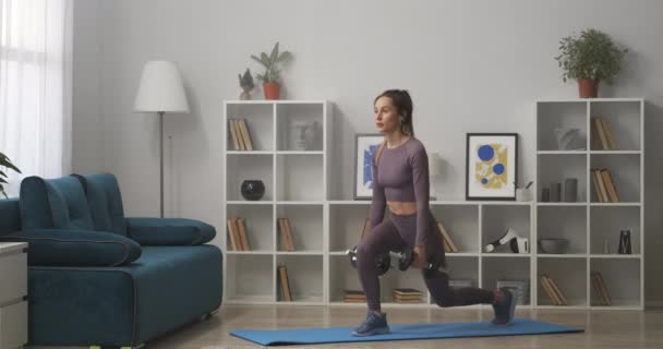 Sexy sportswoman robi ćwiczenia dla pośladki w domu, squatting z hantlami w rękach, utrzymanie sprawności i utraty wagi — Wideo stockowe