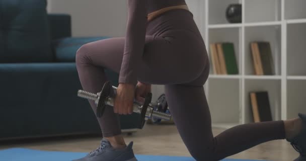 Vrouw doet hurken met halters, training thuis, close-up zicht op het lichaam, slanke benen, billen en rug — Stockvideo