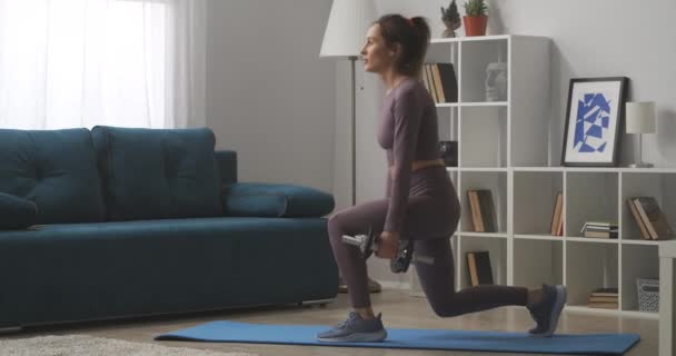 Vista lateral del entrenamiento de la mujer en casa, en cuclillas con pesas en las manos, mantenerse en forma, fitness y bienestar — Vídeos de Stock