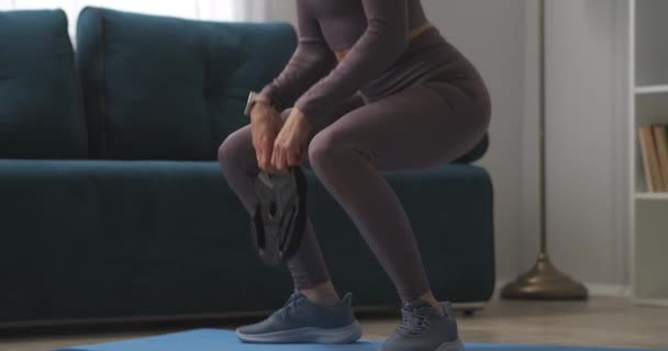 Slanke benen van sportvrouw training thuis, hurken met gewicht in handen, wellness en afvallen, fitness in het weekend, sportieve en gezonde levensstijl — Stockvideo