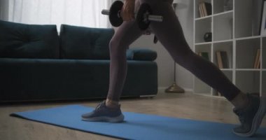 Sporcu kadın dambıllarla çömeliyor, evde antrenman yapıyor, seksi kadın vücudu, sağlık ve sağlıklı yaşam tarzı, formda kalın.