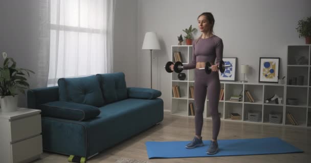 Домашняя тренировка с гантелями для хорошей формы тела, спортивная женщина тренирует квартиру, здоровый образ жизни — стоковое видео