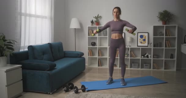 Sportovní dáma s činkami v obývacím pokoji, domácí cvičení pro dobrou kondici těla, sportovkyně zvedá činky — Stock video