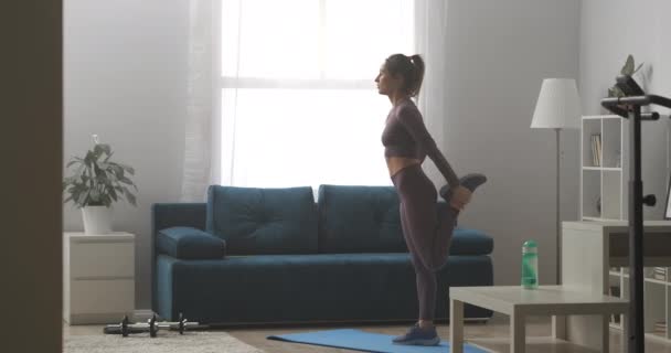 Avkopplande sportig kvinna dricker vatten under pausen hemma träning, står i vardagsrummet på solig dag — Stockvideo