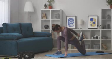 Genç, sportif bir kadın, kaslarını esnetiyor, evde egzersiz yapıyor, spor yapıyor ve sağlıklı bir yaşam sürüyor.