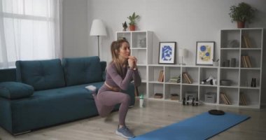 Hafta sonları oturma odasında egzersiz yapan sporcu kadın, spor ve sağlıklı bir yaşam tarzında, dairede uzun pozlar veriyor.