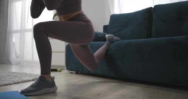 Вид крупным планом стройных ног молодой женщины, тренирующейся дома, спортсменка делает упражнения для мышц ног — стоковое видео
