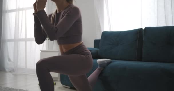 Modèle de fitness sexy s'entraîne dans le salon, faire des squats, vue rapprochée sur la partie inférieure du corps féminin, lapin de gymnase — Video