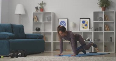 young sexy lady is training ass and legs, doing exercises with fitness elastic band, home workout, standing on hands and knees