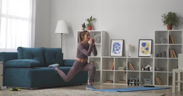 Vrouw is hurken in de woonkamer van modern appartement, training en het doen van lichamelijke oefening voor gezondheid en schoonheid, volledige lengte — Stockvideo