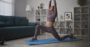 Kadın evde yoga yapıyor, sabah oturma odasında Asya dansı yapıyor, egzersiz yapıyor.