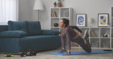 Kadın bacak kaslarını çalıştırmak için egzersiz yapıyor, evde antrenman yapıyor, vücudun güzelliğini önemsiyor.