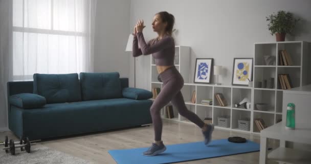 Kobieta skacze i kuca, trening sam w domu, fitness w kwarantannie i zamknięcie, utrzymanie sprawności i smukłej sylwetki — Wideo stockowe