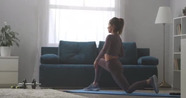 家でストレッチする体操女は筋肉を伸ばすヨガアサナ戦士ポーズをしてる — ストック動画