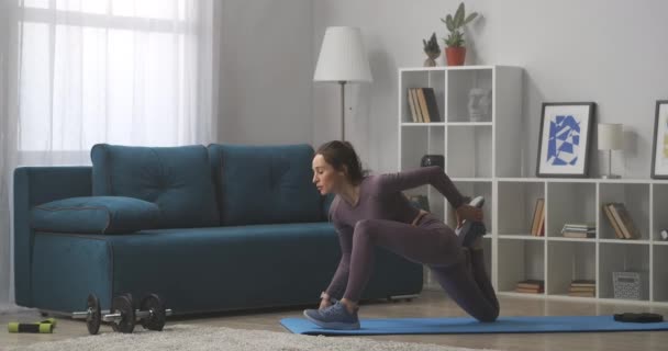 Giovane donna sportiva sta praticando yoga a casa, facendo asana per lo stretching del corpo, allenamento nel fine settimana in auto-isolamento — Video Stock