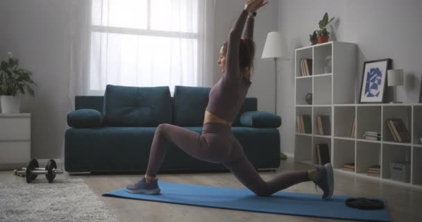 Sottile donna sportiva si allena da sola a casa, allungando l'allenamento per la flessibilità articolare e la salute del corpo — Video Stock