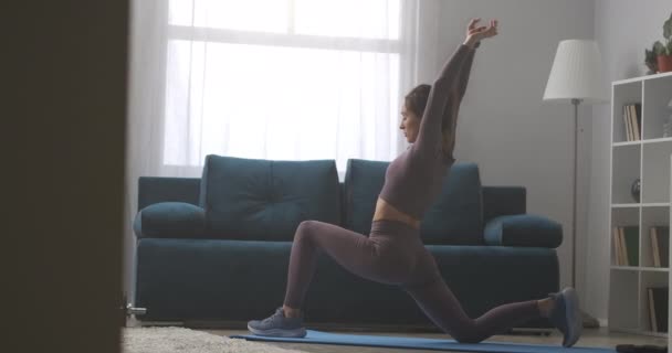 Treinamento de fitness em casa, jovem está praticando ioga asana no chão na sala de estar na manhã — Vídeo de Stock