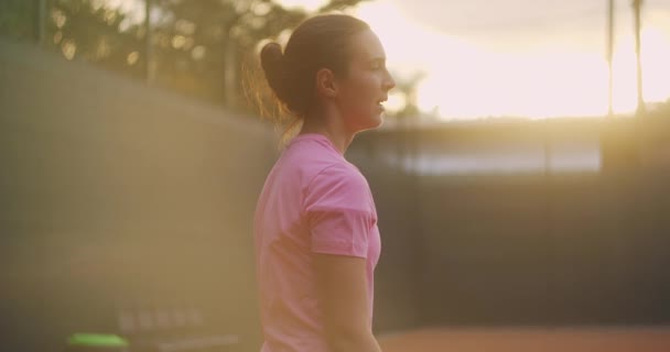 A menina fica curvada até a cintura após um intenso treino de tênis, se endireita e respira tênis fortemente cansado — Vídeo de Stock