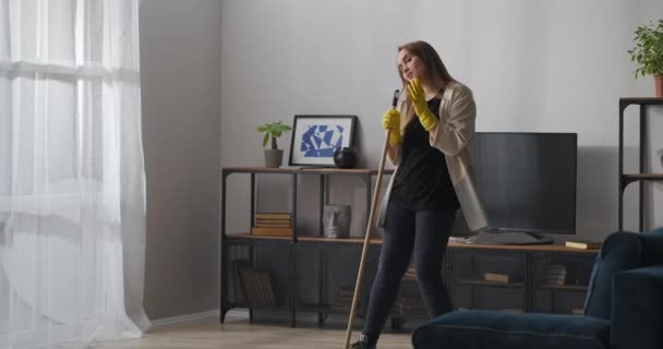 Tonårstjej sjunger i mopp som i mikrofon, tvättar golv och dansar i lägenhet, bra och glad stämning, hjälp runt huset — Stockvideo