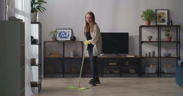 Ajuda em casa, a mulher está lavando o chão no quarto do apartamento moderno com interior calmo, arrumação e limpeza — Vídeo de Stock