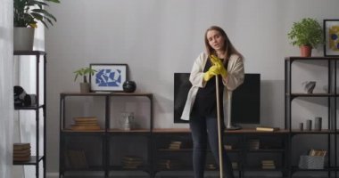 Komik bir apartman dairesi, genç bayan şarkı söylüyor mikrofon olarak paspası kullanıyor, süperstar gibi dans ediyor, eğleniyor.