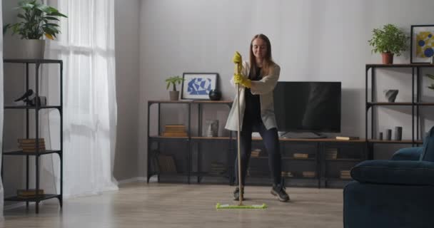 Vrouwelijke huishoudster danst met dweil tijdens het schoonmaken van huis, wasvloer, vreugde en plezier tijdens het huishouden — Stockvideo