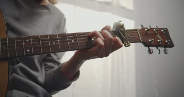 Tiro medio de joven músico practicando la guitarra. Mujer con anillos tocando la guitarra acústica con hermosa luz del sol. — Vídeo de stock