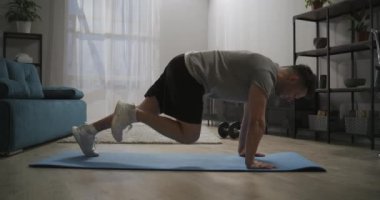 Evde koşmak, spor yapmak, ellerini yere yaslamak ve bacaklarını oynatmak, apartman dairesinde, oturma odasında antrenman yapmak.