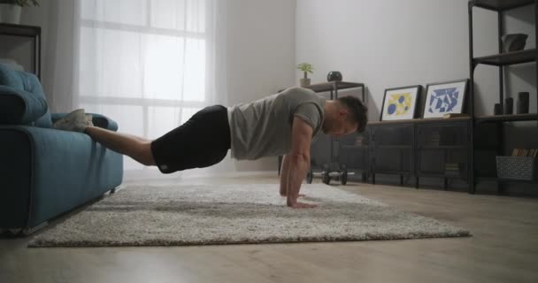 Home gym, man is doing push-ups in apartment at morning, workout for biceps, strong and muscular sportsman — Stock Video