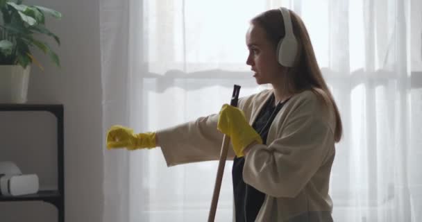 Glad och positiv dam sjunger för mopp och dans i vardagsrummet, städning och städning, städning och tvättgolv — Stockvideo