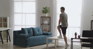 Apartmanda spor, yetişkin atletik adam spor malzemeleri gibi masayı kullanıyor, onu kaldırıyor ve spor ve sağlıklı yaşam tarzını düşürüyor.
