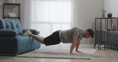 Güçlü ve kaslı kollar için idman, evde egzersiz, yakışıklı sporcu ağırlığını yerden kaldırıyor, formda kalıyor.