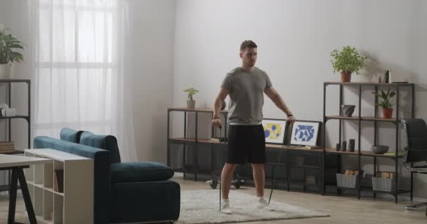 Homme athlétique s'entraîne à la maison, en utilisant des bandes élastiques pour l'entraînement de force, en gardant une bonne condition physique, musculation — Video