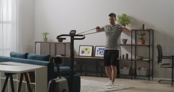 Προπόνηση με λαστιχάκια στο δωμάτιο, ο άνθρωπος προπονείται στο σπίτι, υγιεινό τρόπο ζωής, σωματική άσκηση για την υγεία — Αρχείο Βίντεο